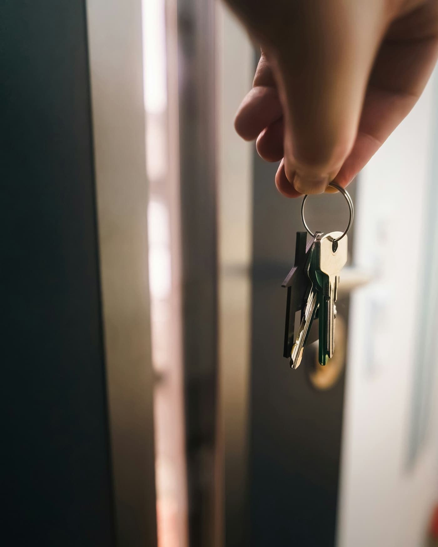 Main tenant un trousseau de clés devant une porte ouverte