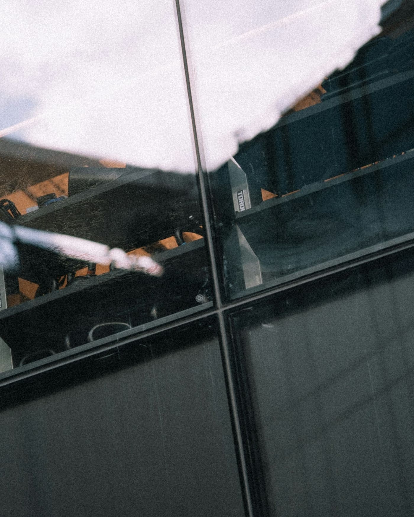 Perche télescopique de lavage de vitres appuyée contre une baie vitrée, vue de l'intérieur
